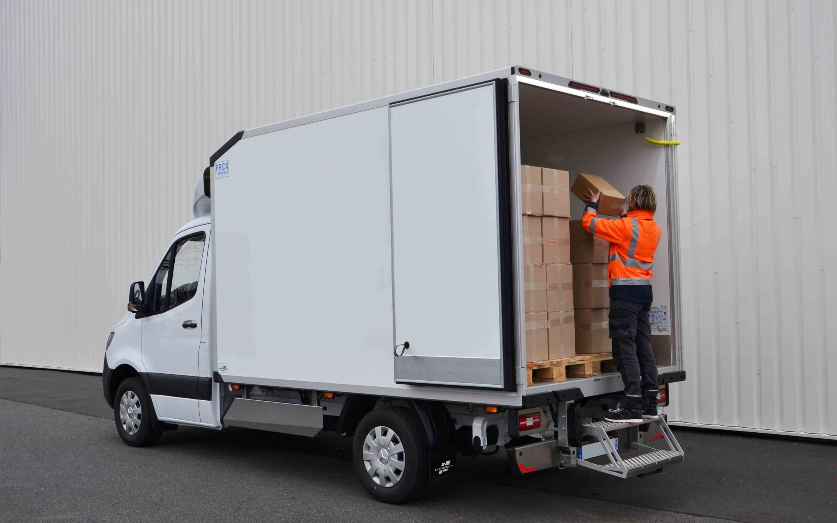 Livreur en train de prendre un colis à l'arrière d'un camion frigorifique