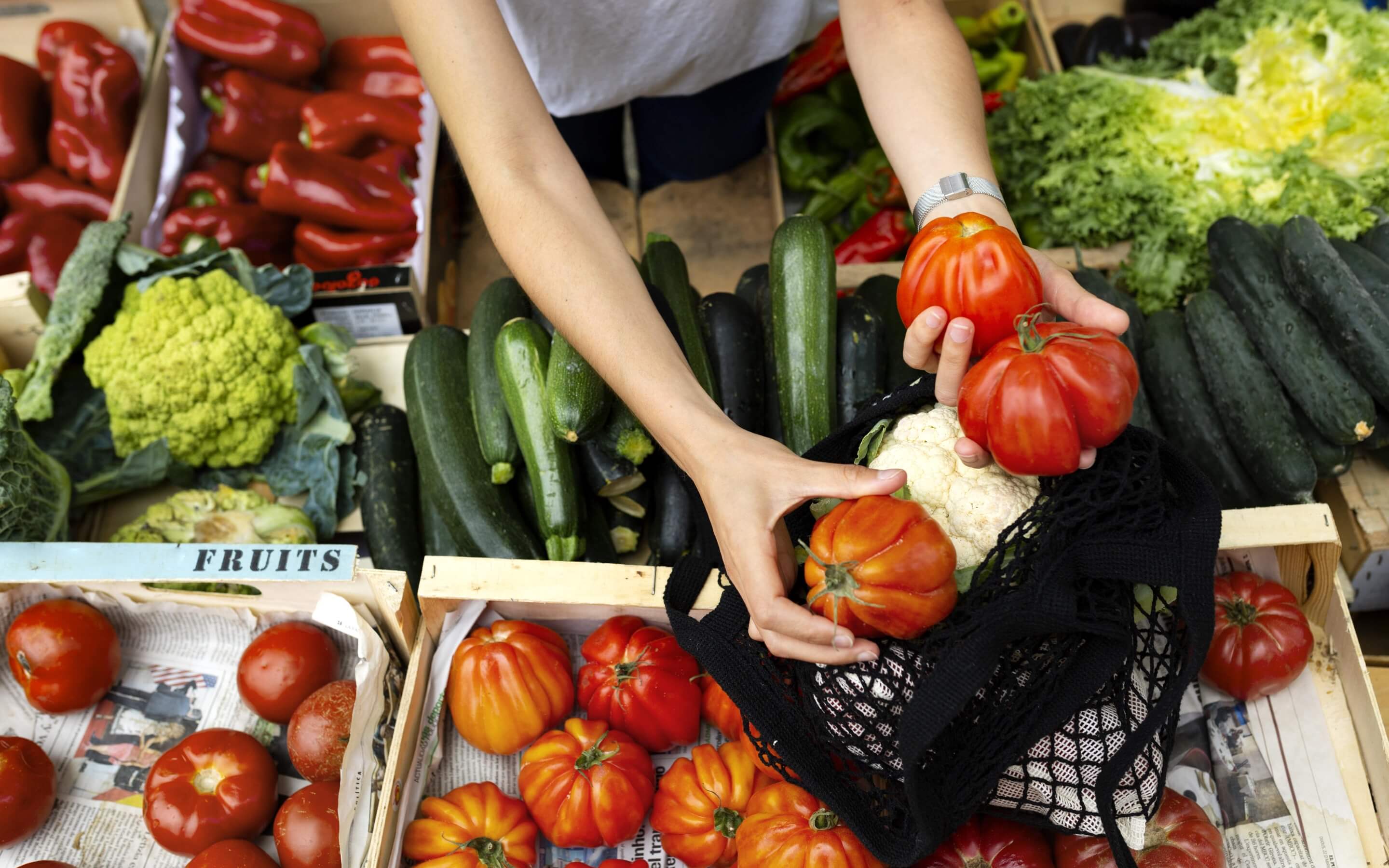 Personne sélectionnant ses fruits et légumes sur une étal de marché