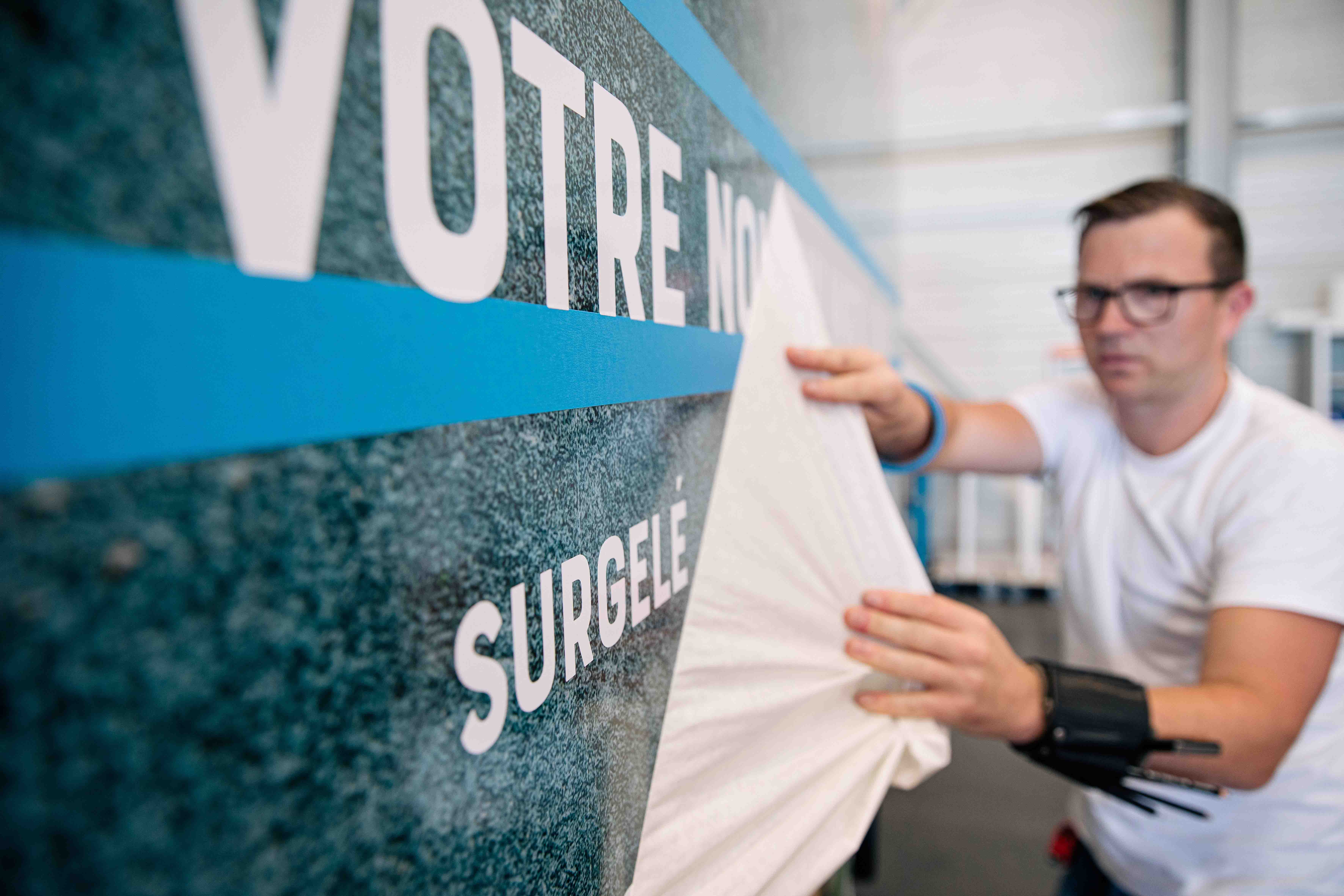 Homme posant une publicité sur une véhicule frigorifique Lecapitaine
