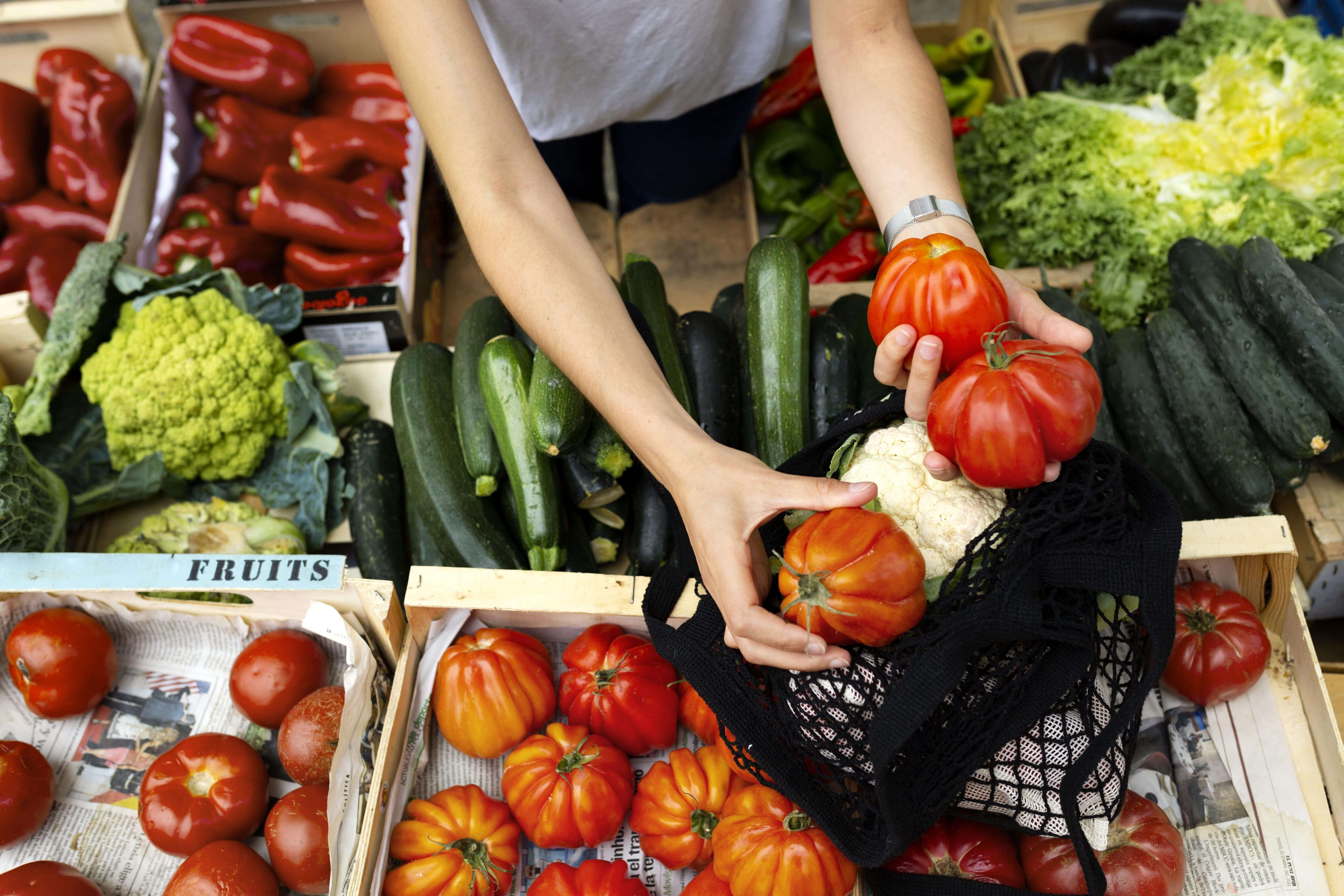 Personne sélectionnant ses fruits et légumes sur une étal de marché